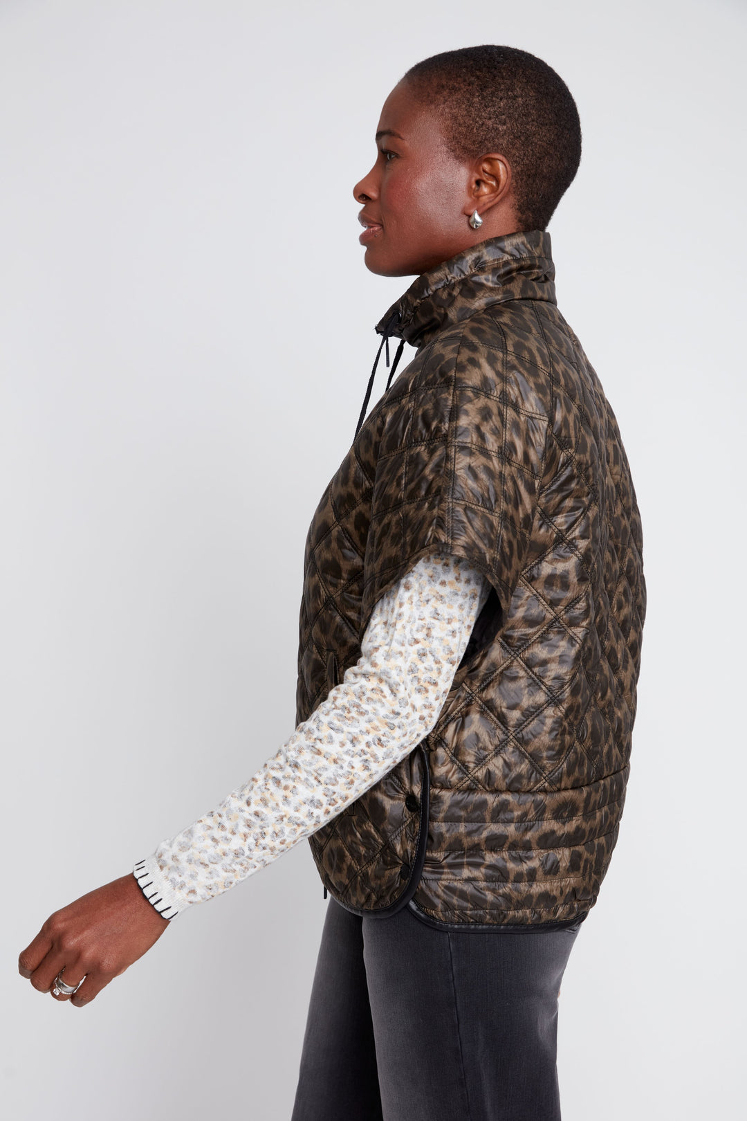 Person wearing a leopard print jacket over a patterned shirt on a white background