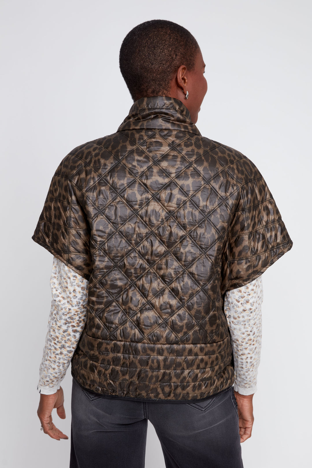 Person wearing a leopard print quilted jacket on a white background