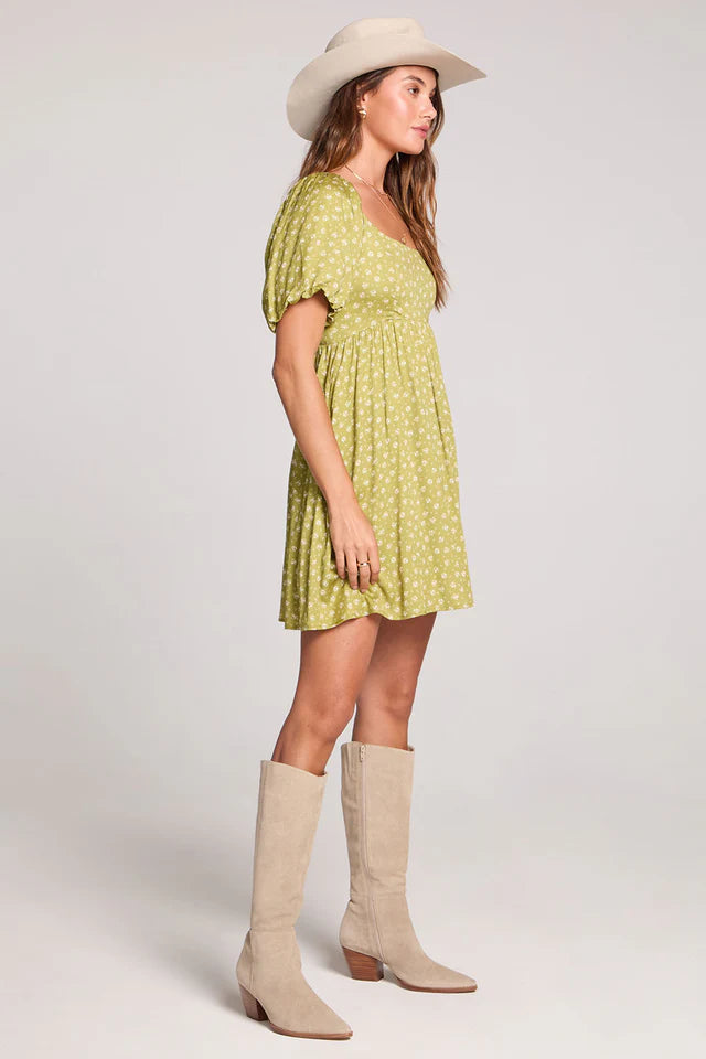 Woman wearing a green dress and beige boots on a white background
