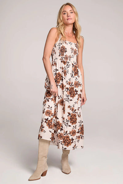 Woman wearing a floral dress with beige boots on a plain background