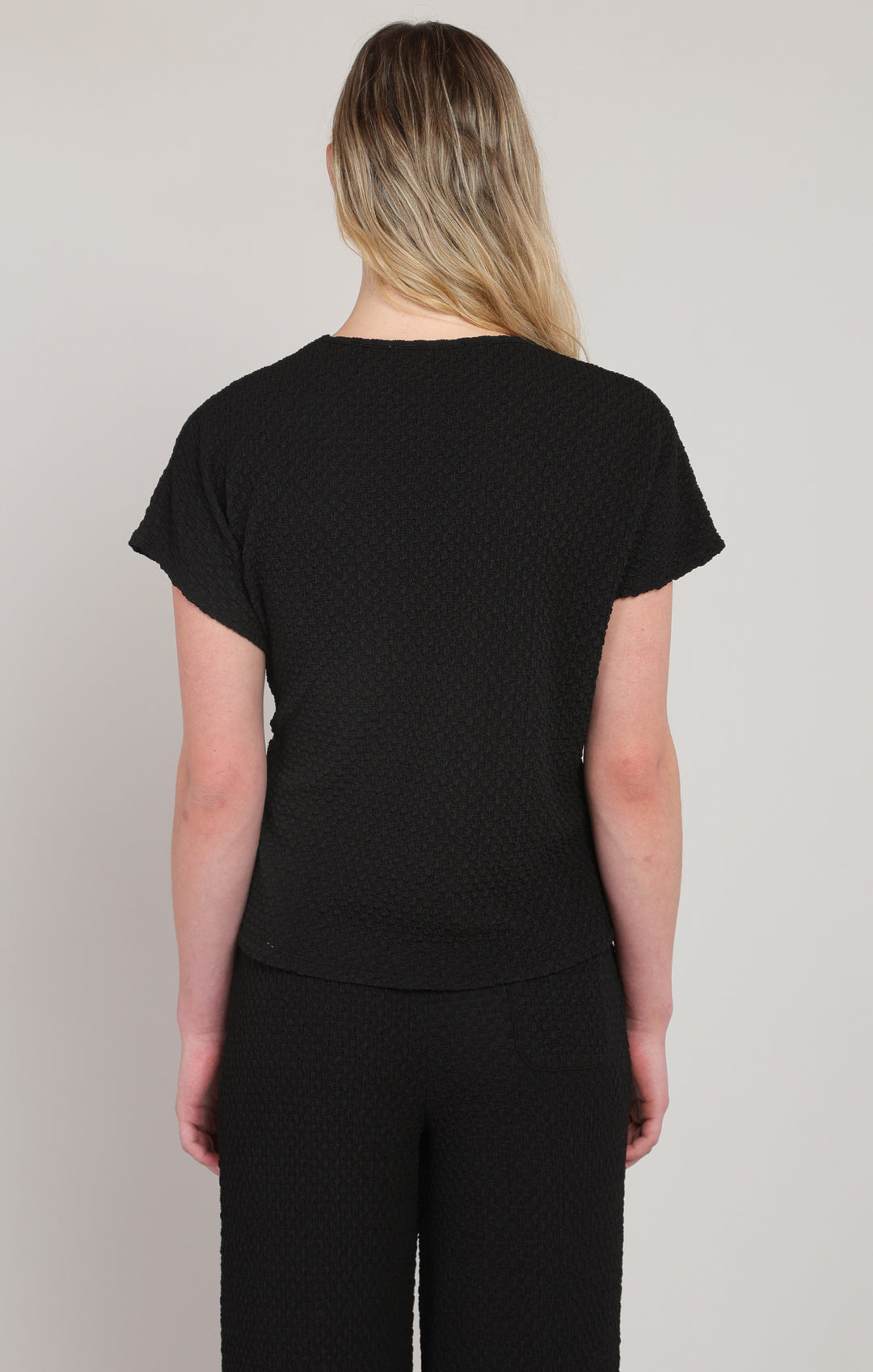 Person wearing a black t-shirt and pants on a plain background