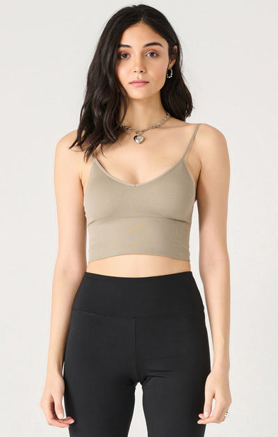 Woman wearing a green crop top and black leggings on a light gray background