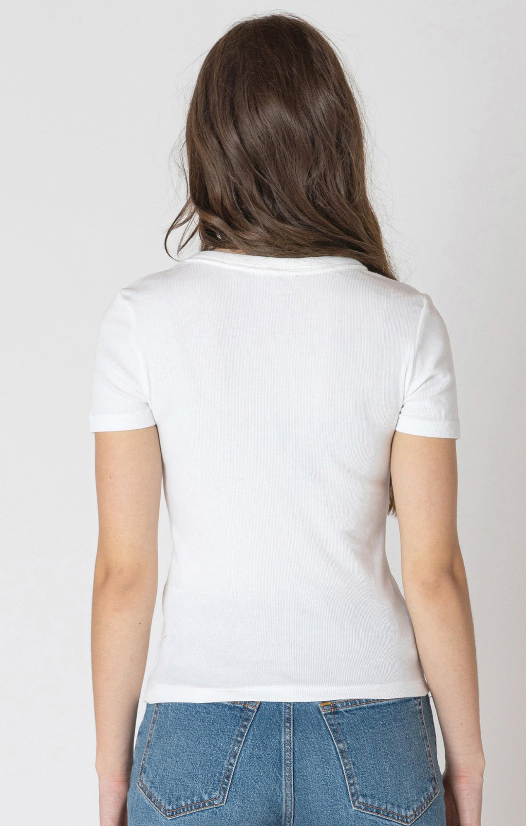 Person wearing a white t-shirt and blue jeans on a plain background