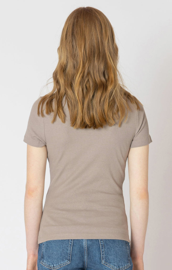 Person wearing a beige t-shirt and blue jeans on a plain background
