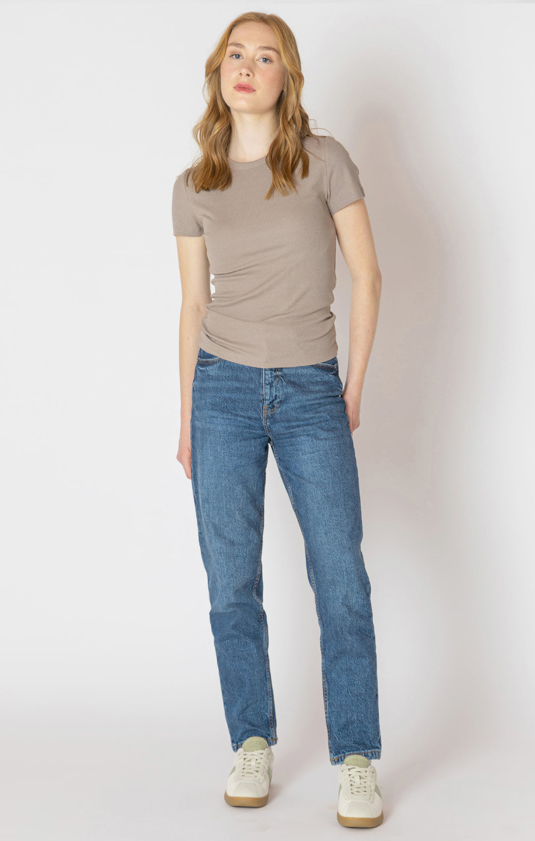 Person wearing a beige t-shirt and blue jeans on a white background