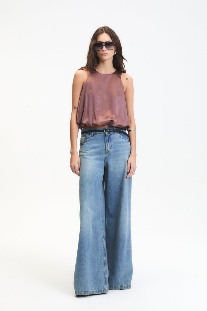 Woman wearing a sleeveless top and wide-leg jeans on a white background