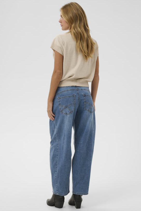 Woman wearing blue jeans and a beige top on a white background