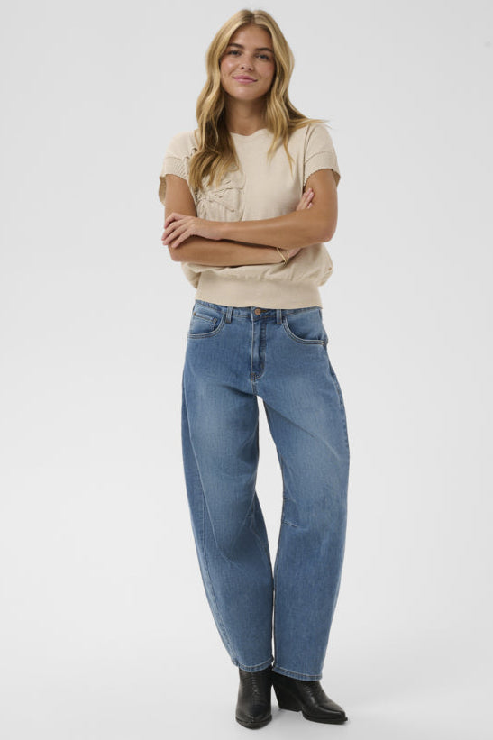Woman wearing a beige t-shirt and blue jeans on a white background