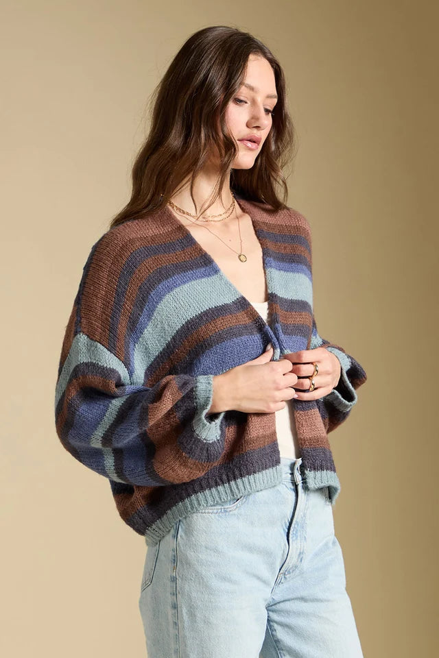 Woman wearing a striped sweater and light blue jeans against a beige background