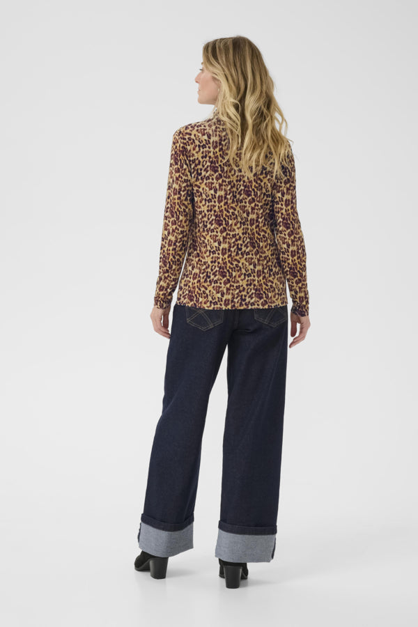 Woman wearing a leopard print top and dark blue pants on a white background