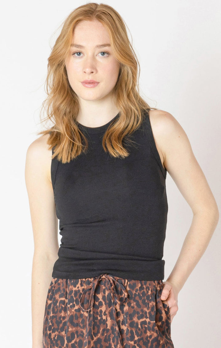 Woman wearing a black sleeveless top and leopard print pants on a white background