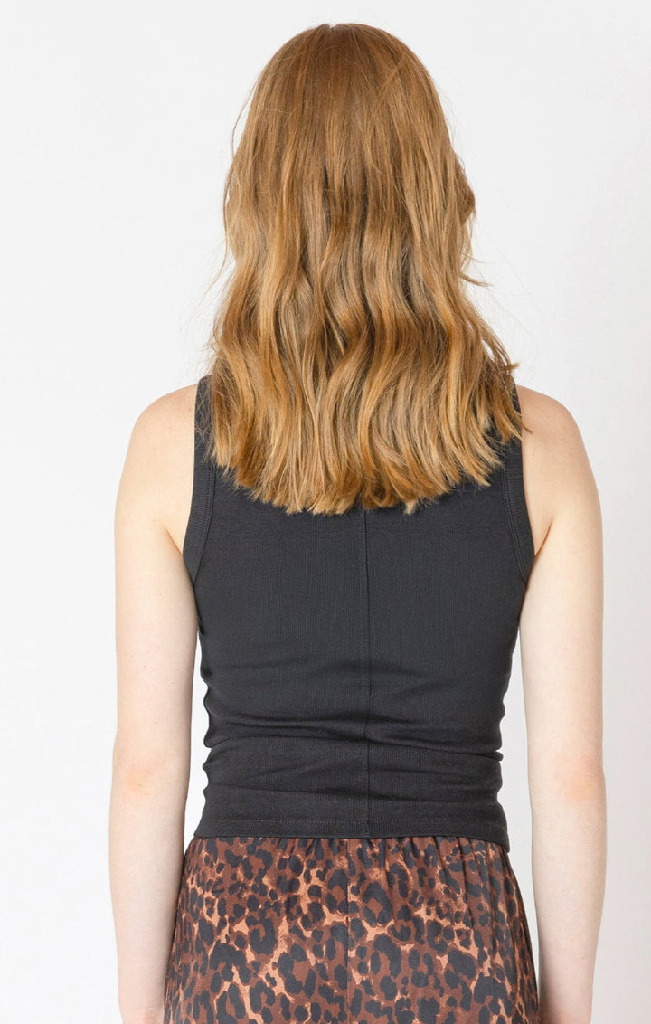 Person wearing a black sleeveless top and leopard print pants on a plain background