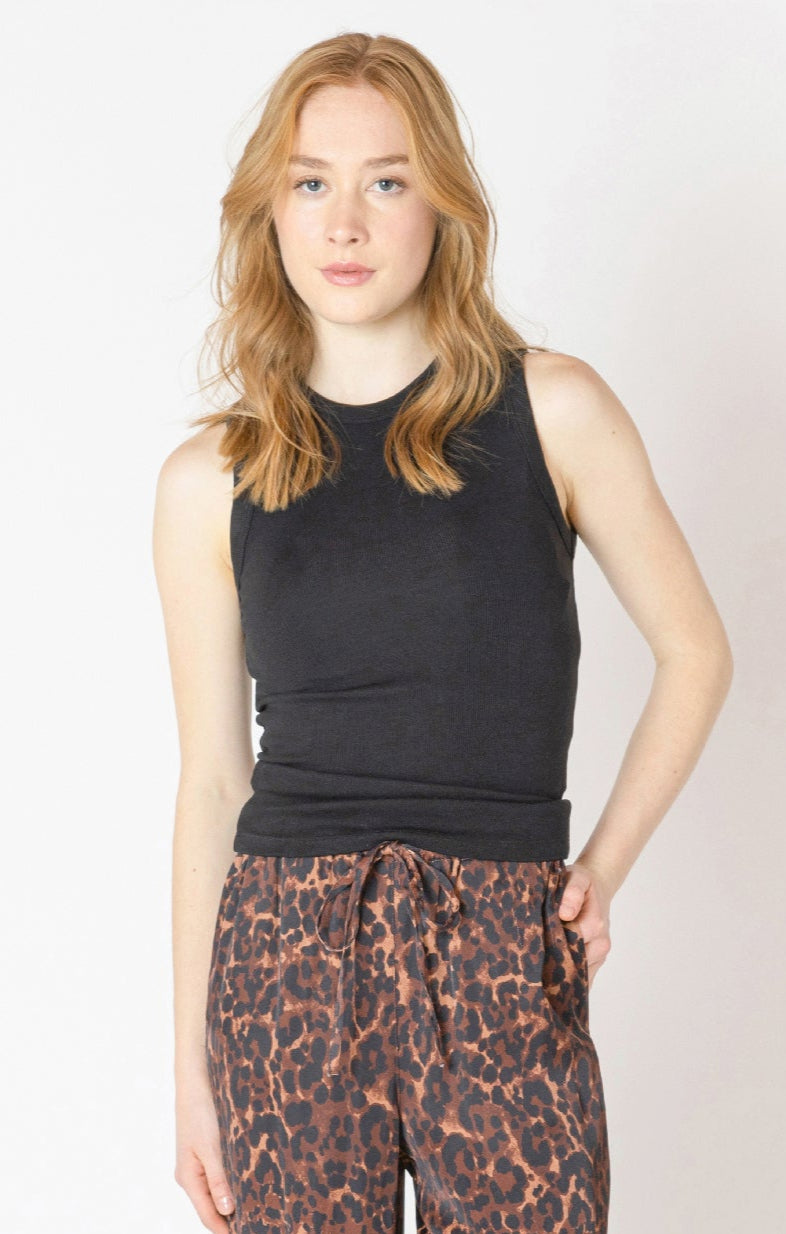 Woman wearing a black sleeveless top and leopard print pants on a white background