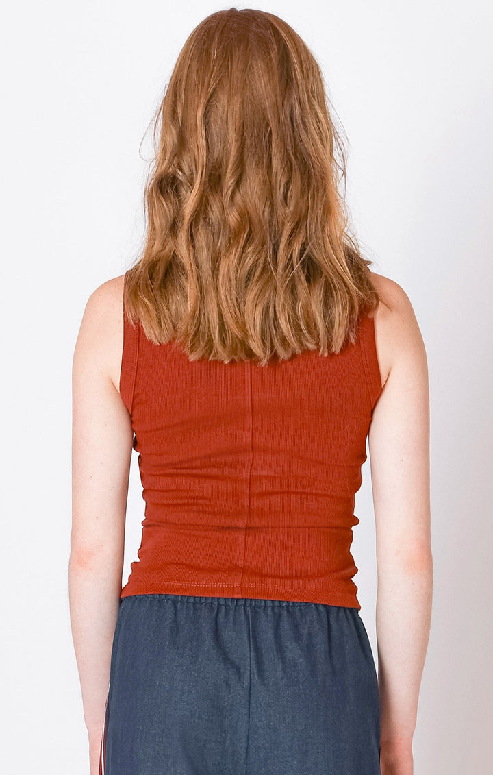 Person wearing an orange sleeveless top and blue skirt on a white background