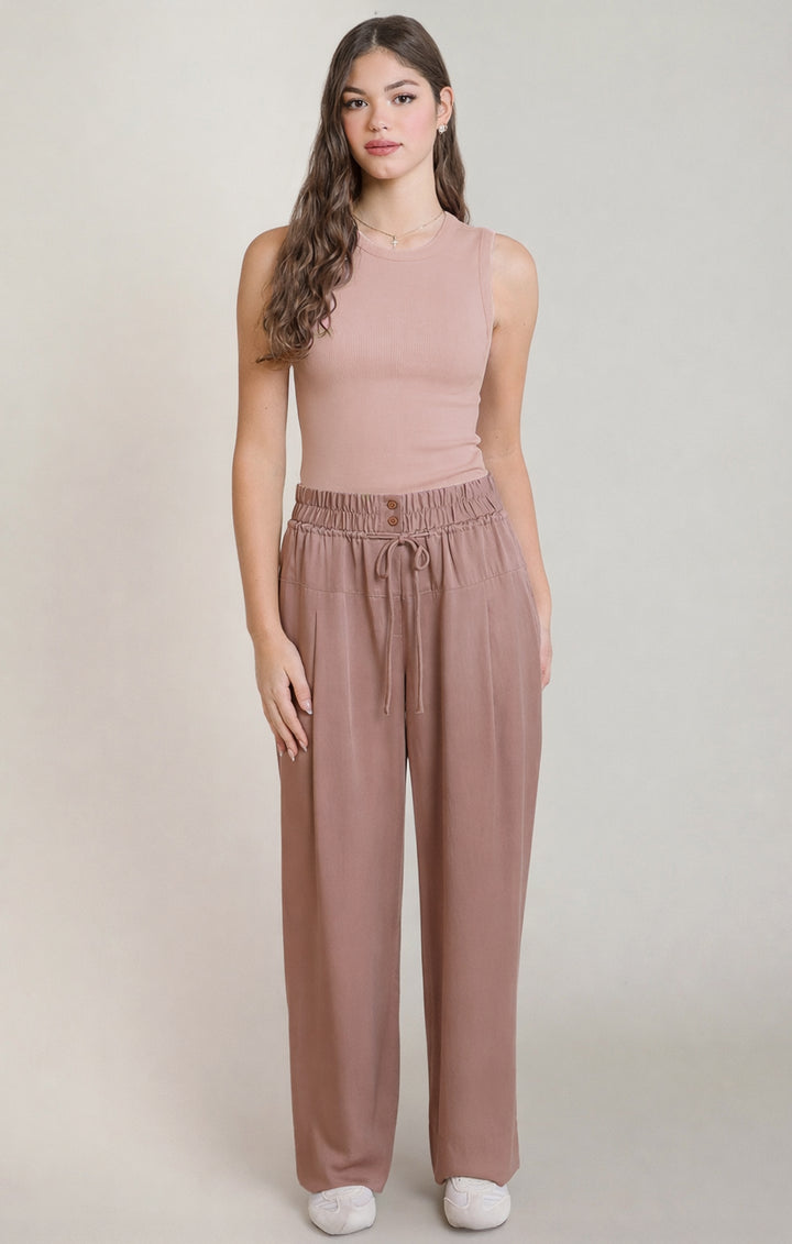 Woman wearing a matching pink top and pants set on a plain background