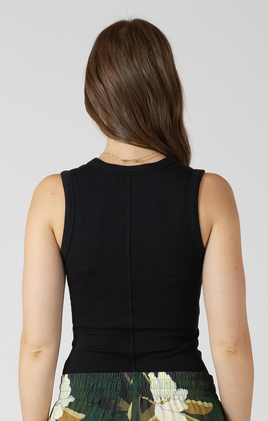 Woman wearing a black top and green floral skirt on a white background