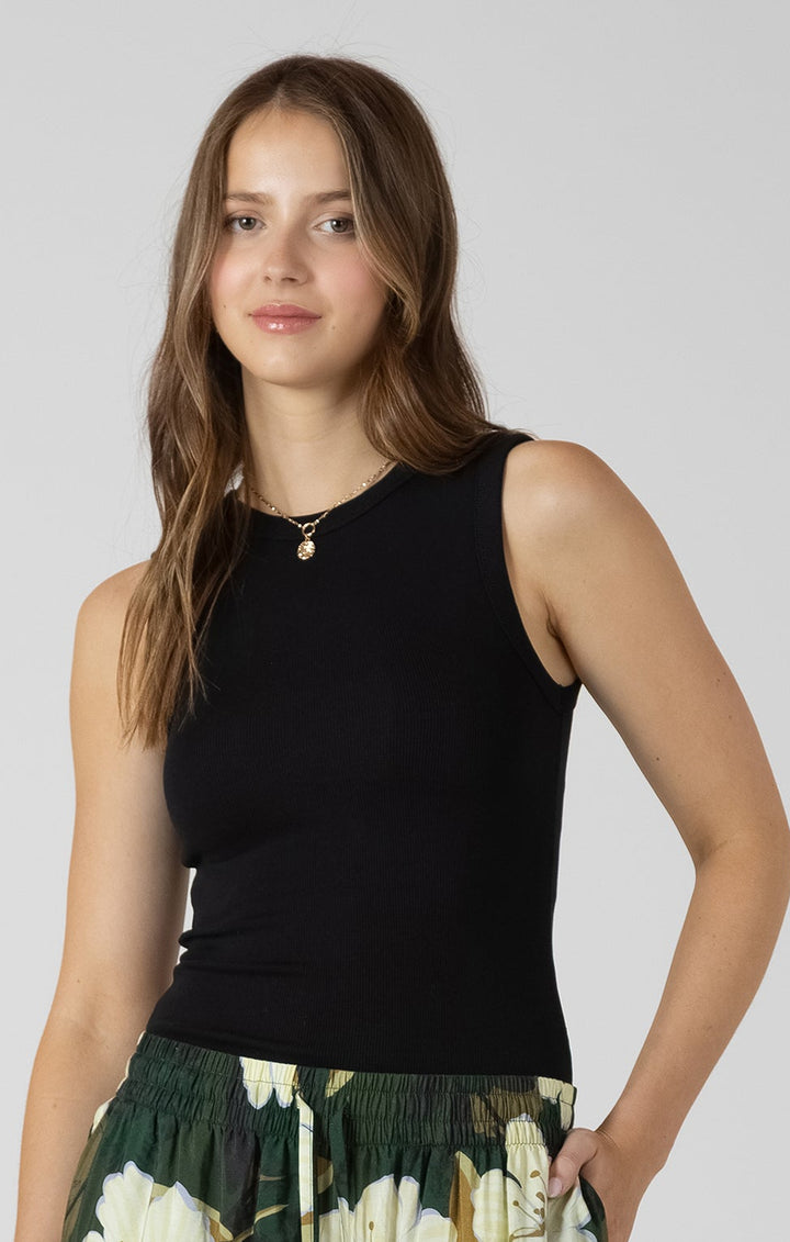 Woman wearing a black sleeveless top and floral skirt on a plain background