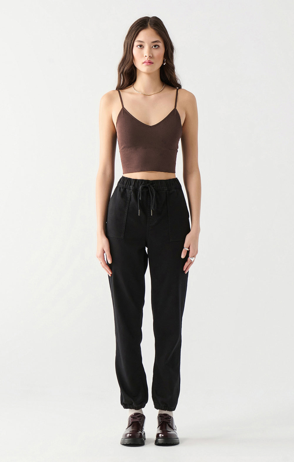 Woman wearing a brown crop top and black pants on a white background