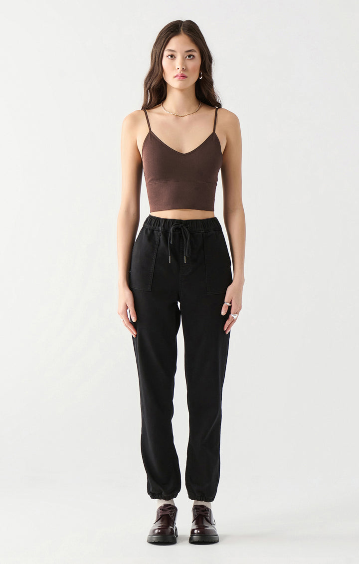Woman wearing a brown crop top and black pants on a white background