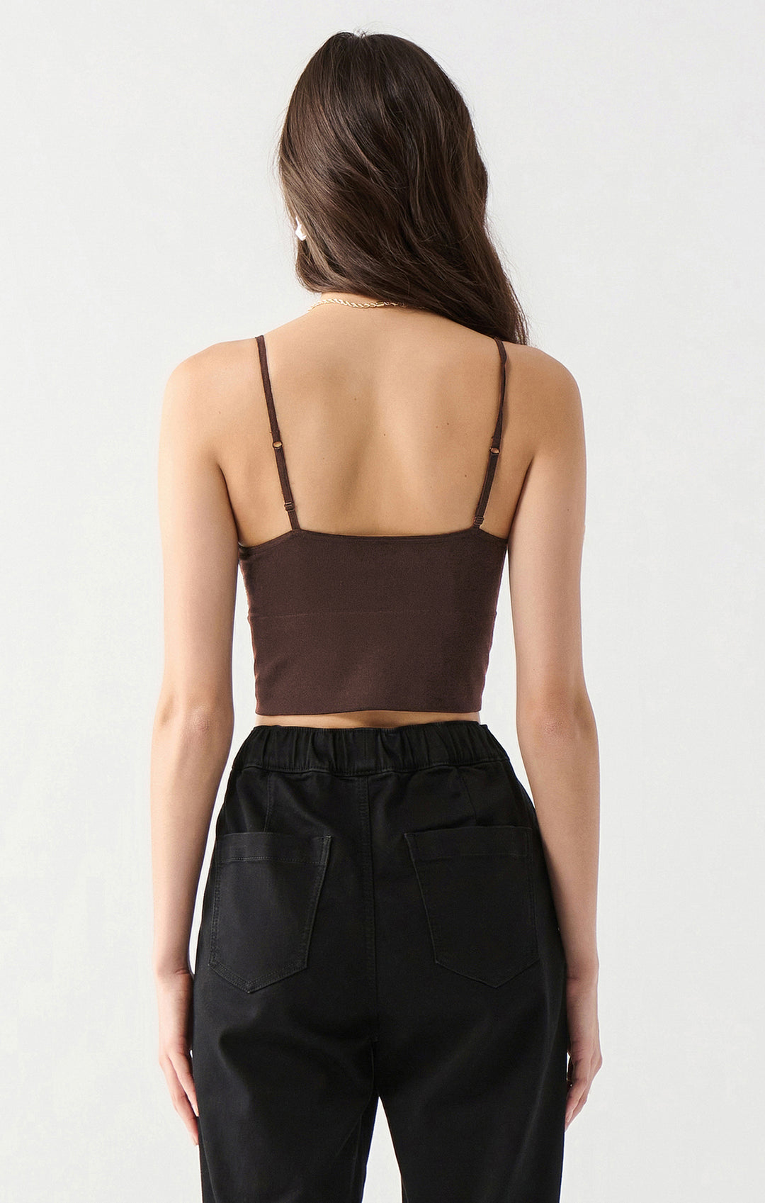 Woman wearing a brown crop top and black pants on a white background