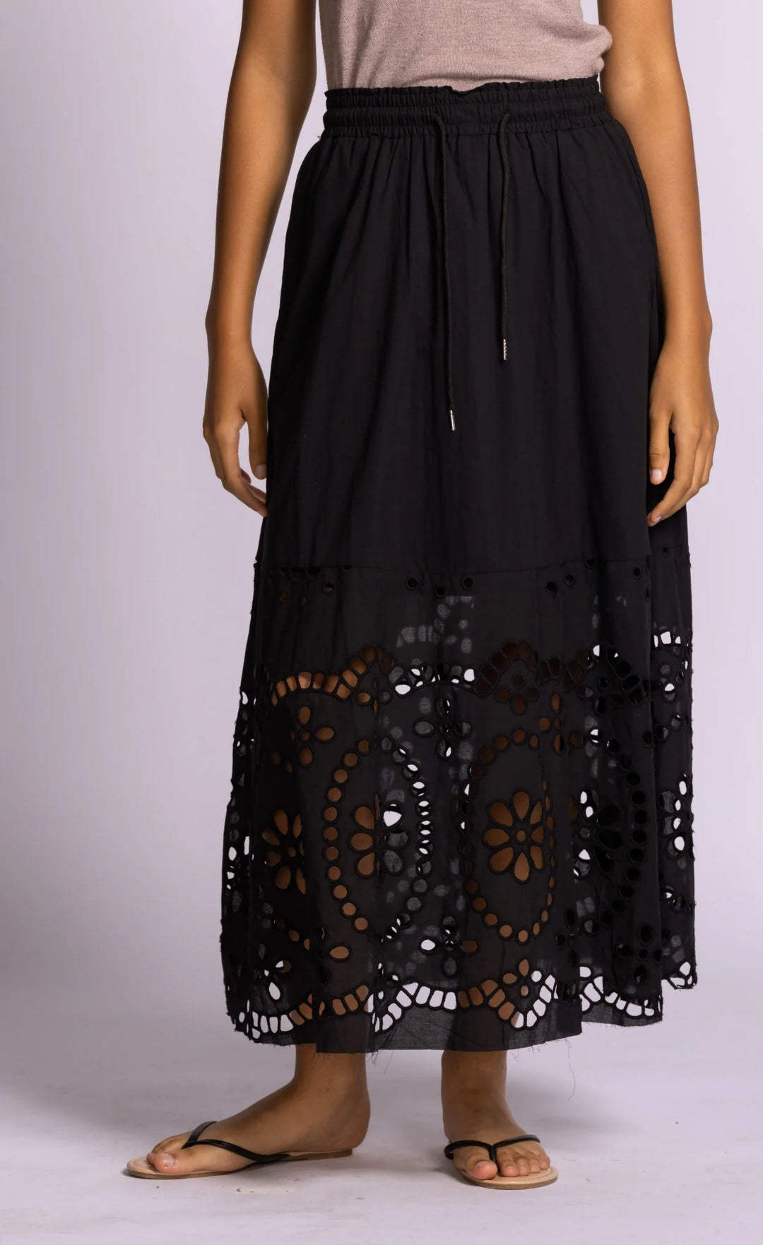 Black lace skirt worn by a person on a light purple background
