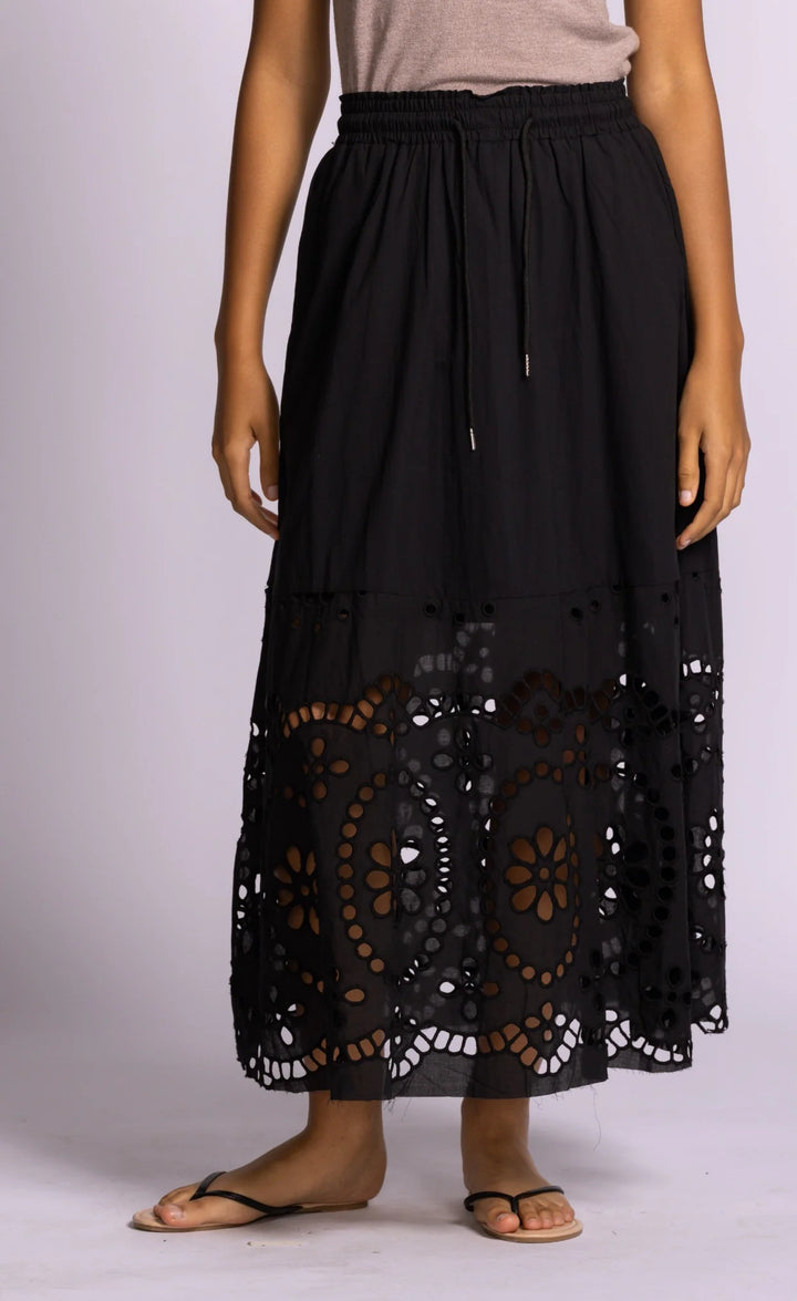 Black lace skirt worn by a person on a light purple background
