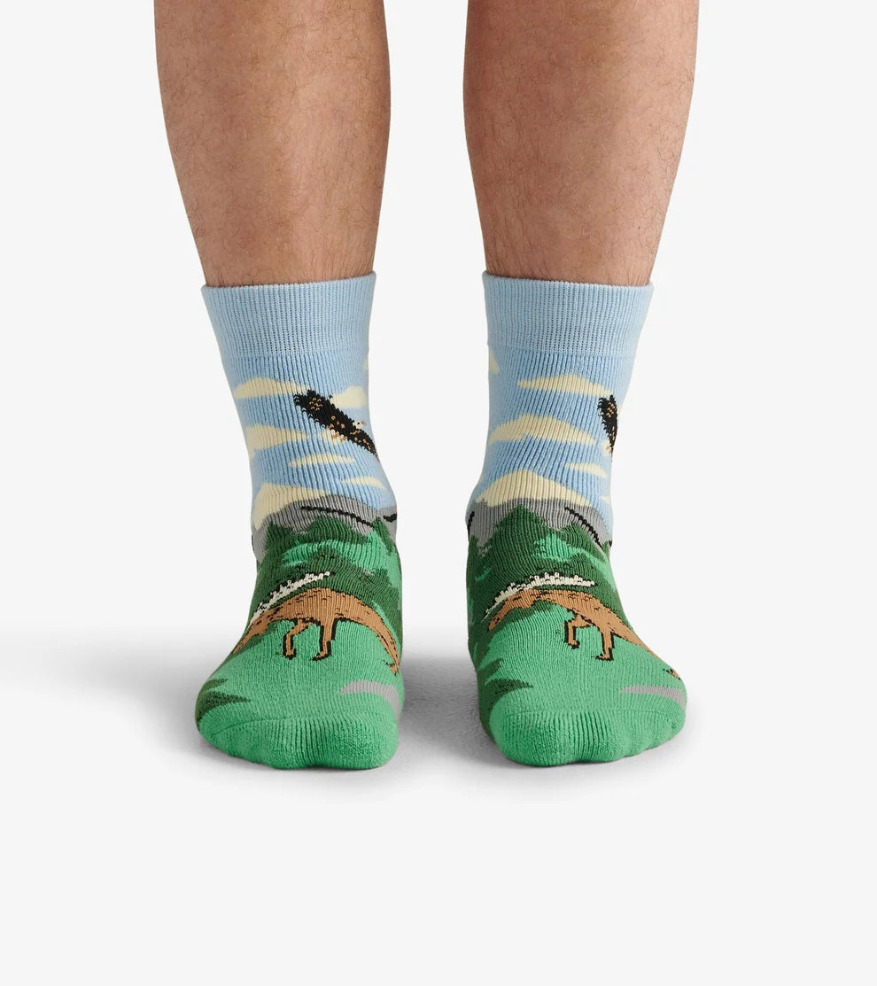 Green socks with dinosaur design worn by a person on a white background