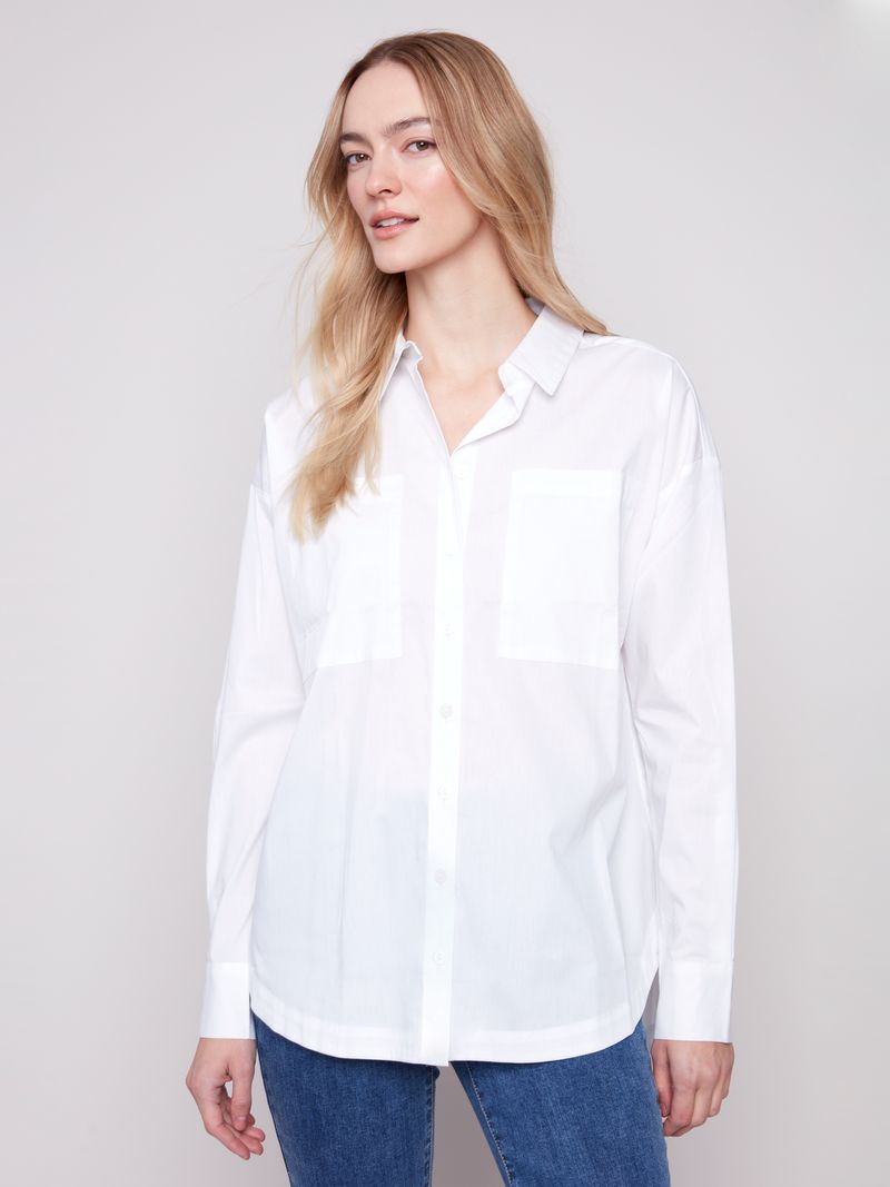 Woman wearing a white shirt and blue jeans against a plain background