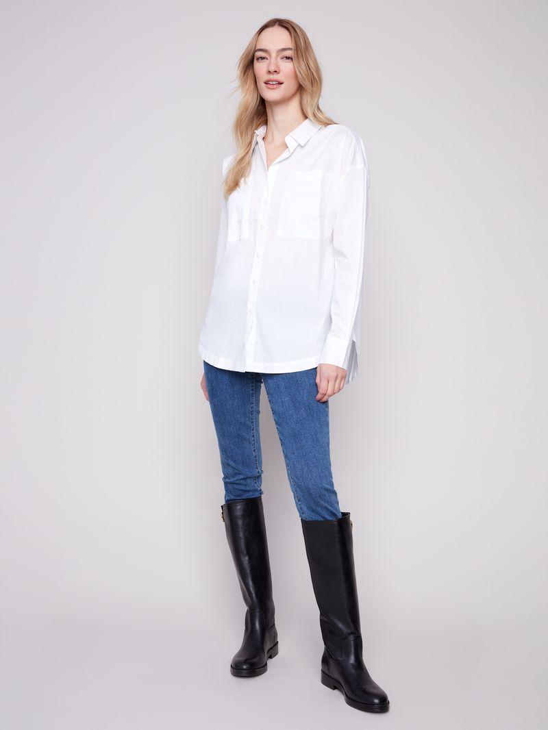 Woman wearing a white shirt, blue jeans, and black knee-high boots on a plain background