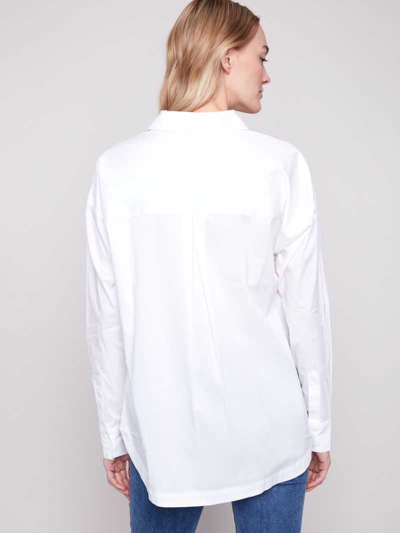 Person wearing a white oversized shirt on a plain background