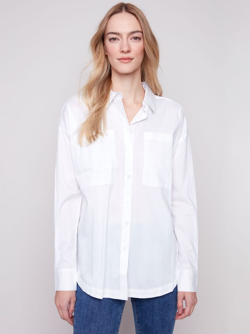 Woman wearing a white shirt and blue jeans against a plain background