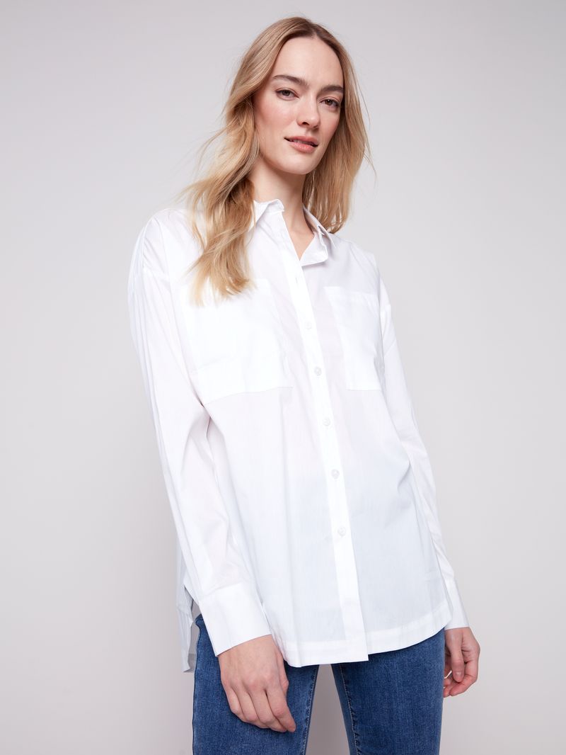 Woman wearing a white shirt and blue jeans against a plain background
