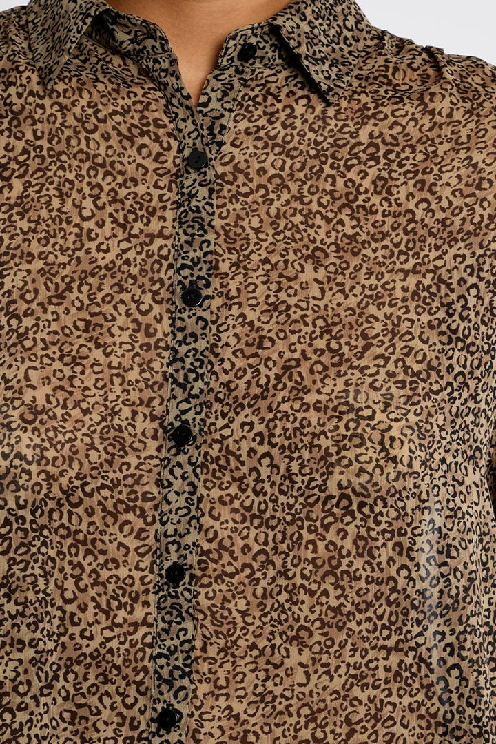 A close-up of a leopard print button-down shirt with a brown and black animal pattern, featuring a pointed collar and dark buttons.