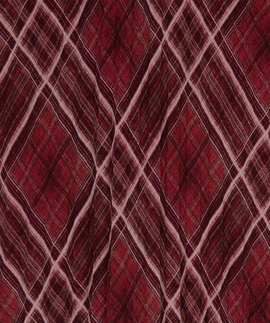 A close-up of a red and burgundy plaid fabric pattern with intersecting diagonal stripes in light pink and dark brown.