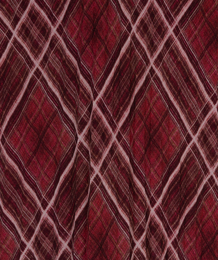 A close-up of a red and burgundy plaid fabric pattern with intersecting diagonal stripes in light pink and dark brown.