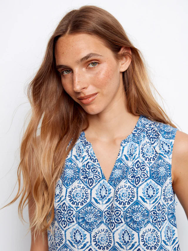 Woman wearing a blue and white patterned sleeveless top against a white background