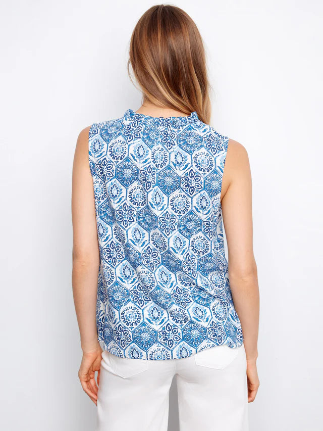 Woman wearing a blue and white patterned sleeveless top against a white background