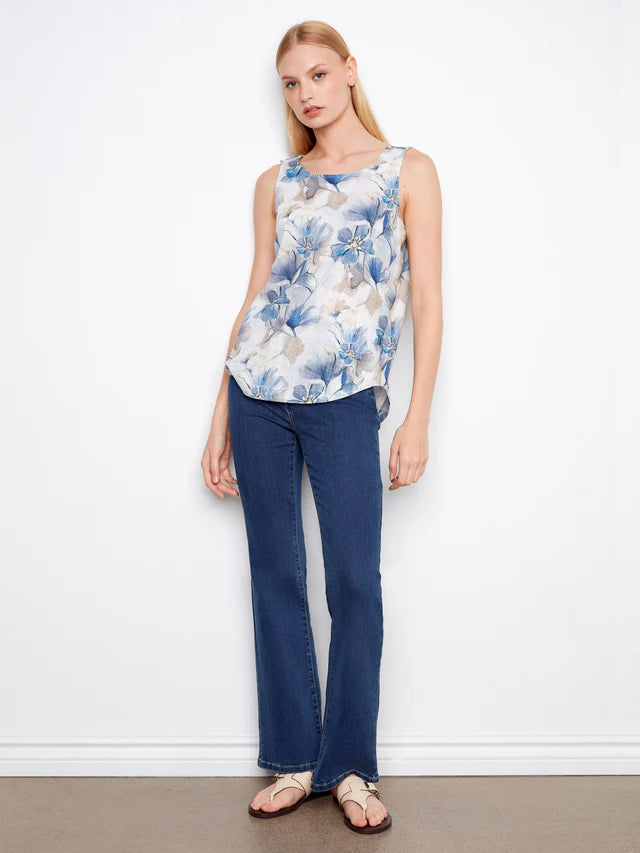 Woman wearing a floral top and blue jeans against a white background
