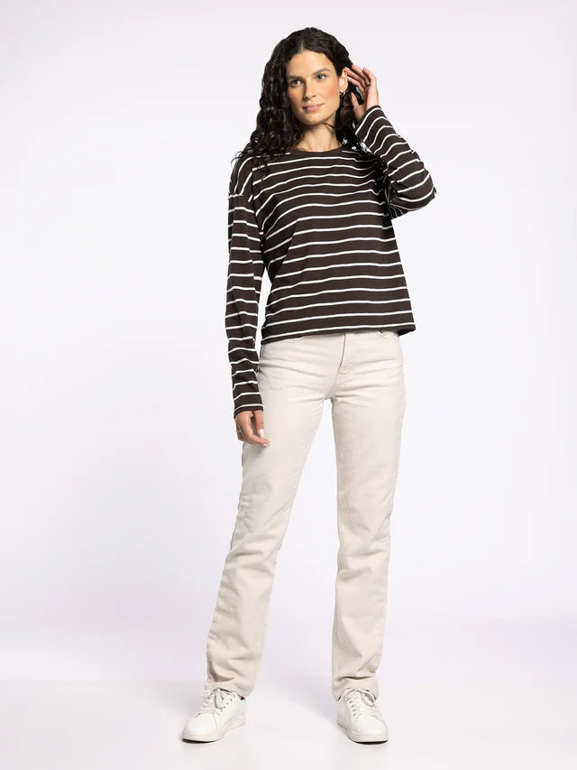 Woman wearing a black and white striped shirt and white pants on a white background
