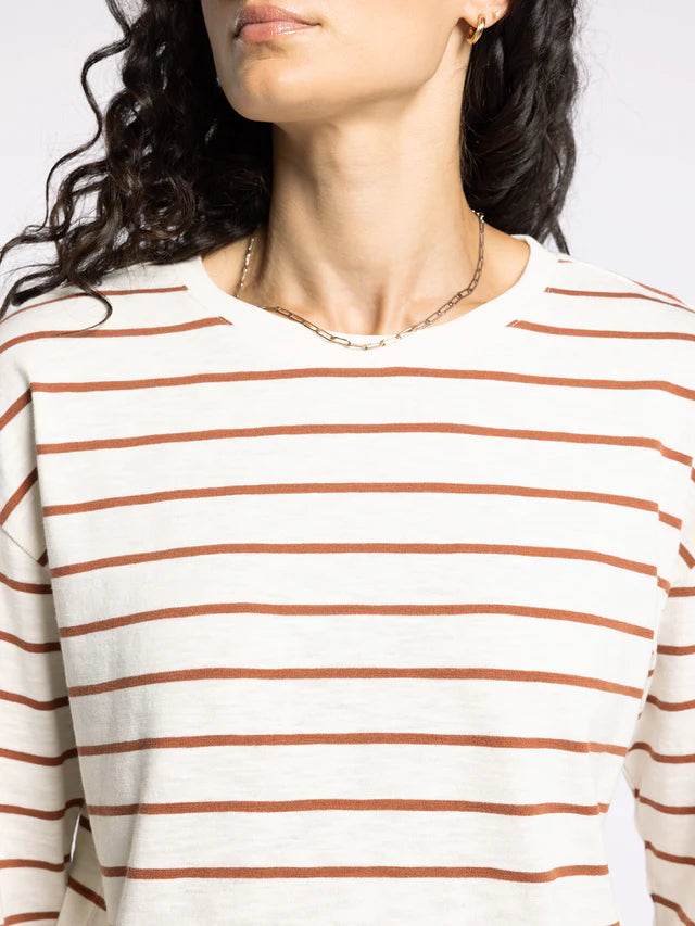 Close-up of a person wearing a white long-sleeve shirt with rust-colored horizontal stripes.