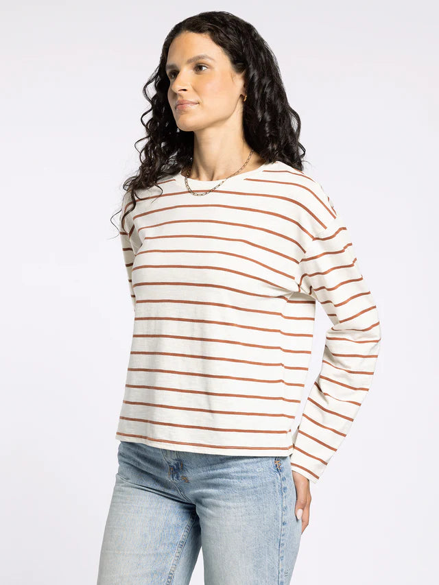 Woman wearing a striped long-sleeve shirt and jeans on a plain background
