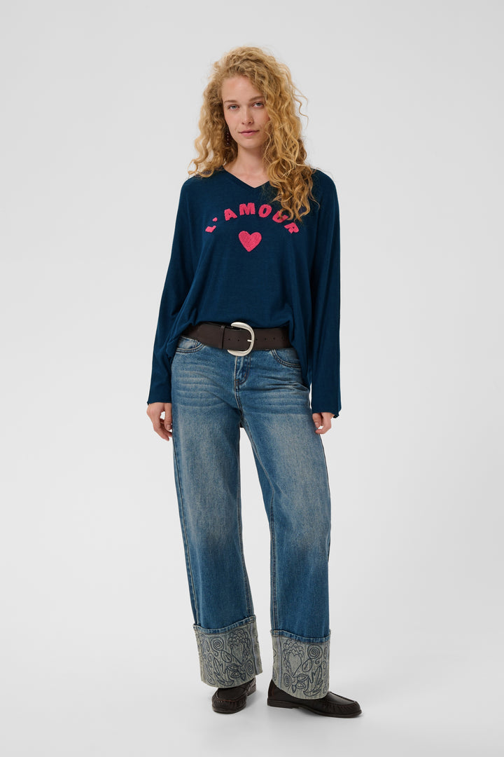 A woman modeling a navy blue long-sleeve V-neck top with a pink &