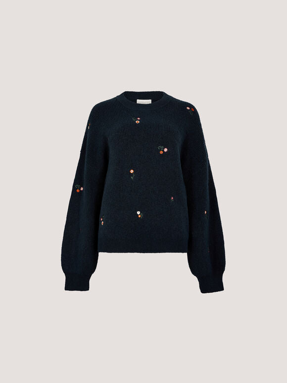 A dark navy blue knit sweater with long balloon sleeves and small scattered embroidered floral details, shown against a solid light gray background.