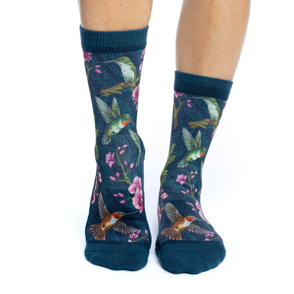 Navy socks with hummingbird and floral pattern worn by a person on a white background