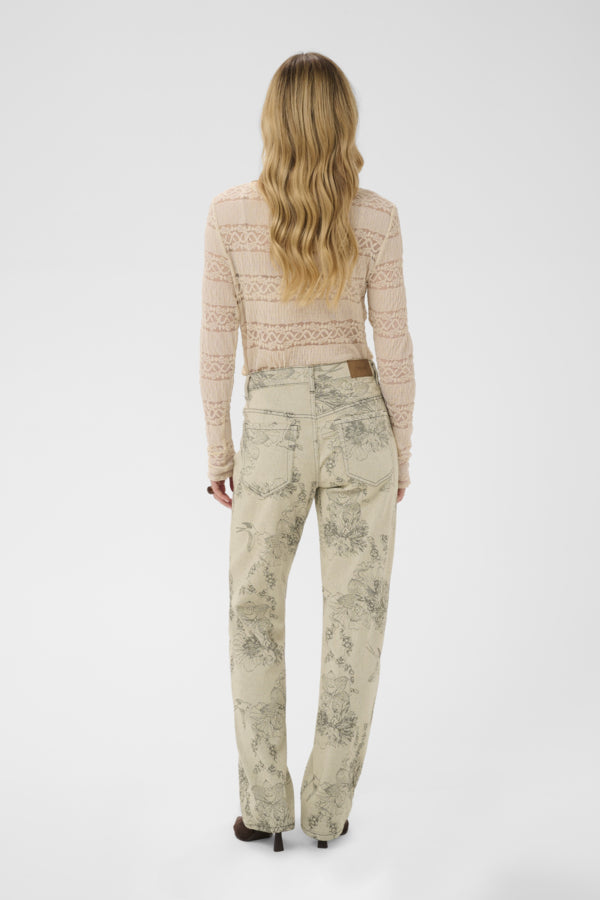 Woman wearing a patterned top and pants on a white background