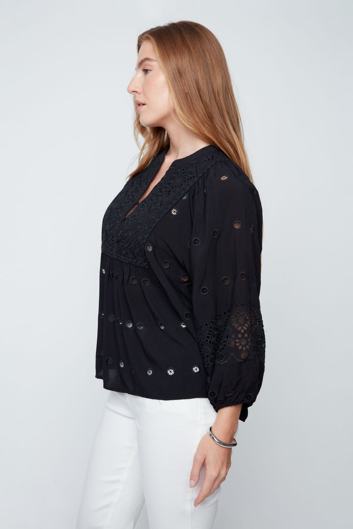 Woman wearing a black blouse with lace details on a white background