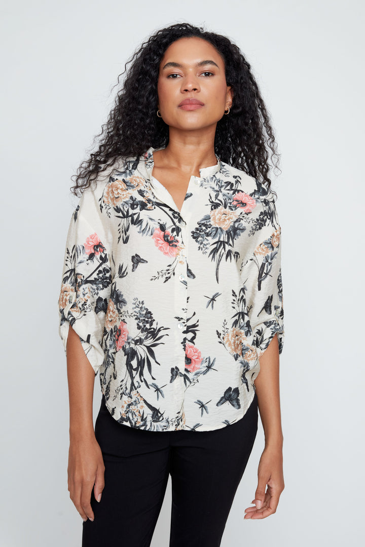 Woman wearing a floral blouse against a plain background
