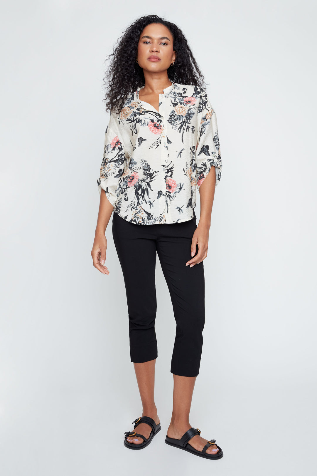 Woman wearing a floral blouse and black pants on a white background