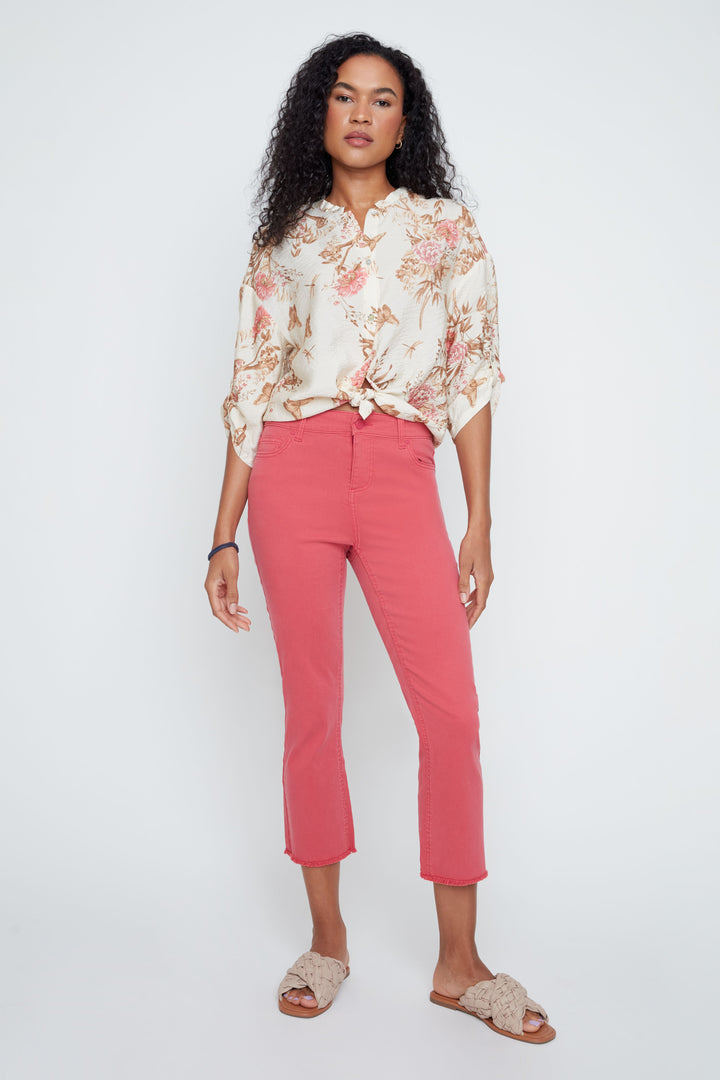 Woman wearing a floral blouse and pink pants on a white background