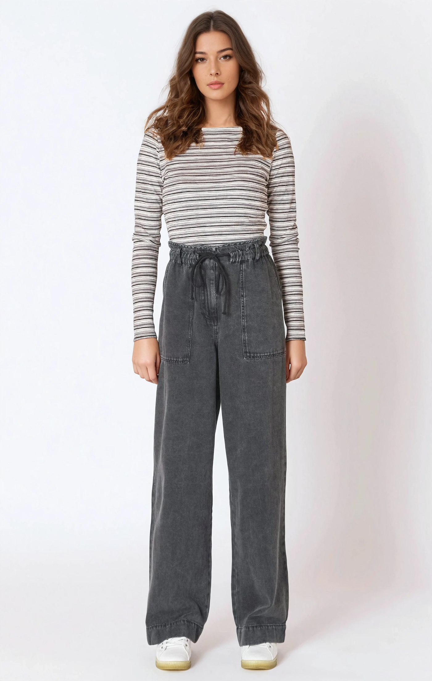 Woman wearing a striped long-sleeve top and gray wide-leg pants on a white background